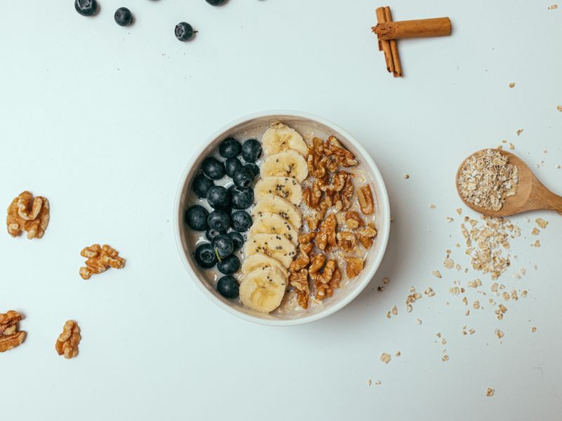 Delicious oatmeal topped with banana, blueberries, walnuts, and chia seeds in a bowl.