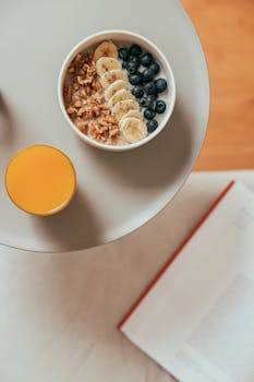 A nutritious breakfast with a fruit bowl and fresh orange juice on a round table.