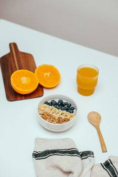 A top view of a healthy breakfast with orange juice, sliced oranges, and a fruit bowl.