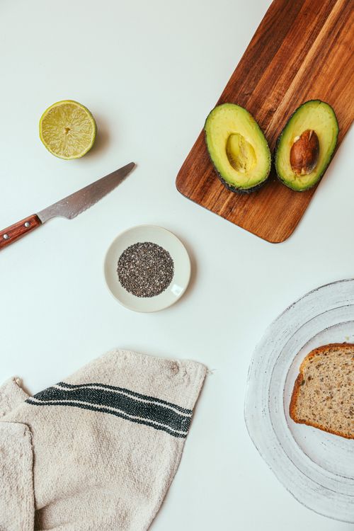 Free Avocado, bread, lemon, and knife on a cutting board with white background. Stock Photo