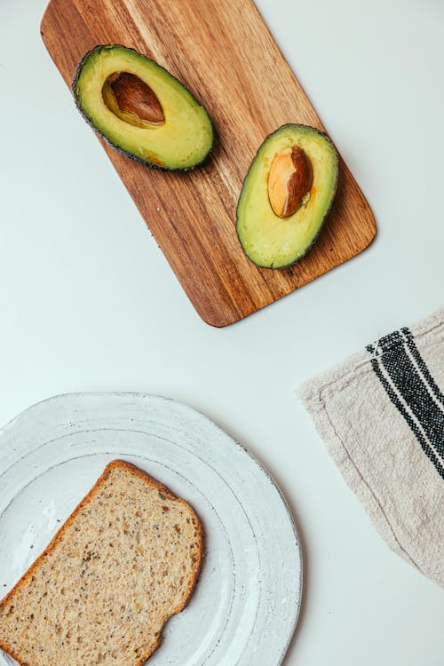 Sliced Avocado and Bread on Wooden Plates