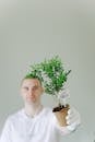 Man in White Crew Neck Shirt Holding Green Plant