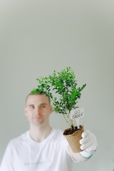 A man holding a potted plant, advocating for a greener lifestyle.