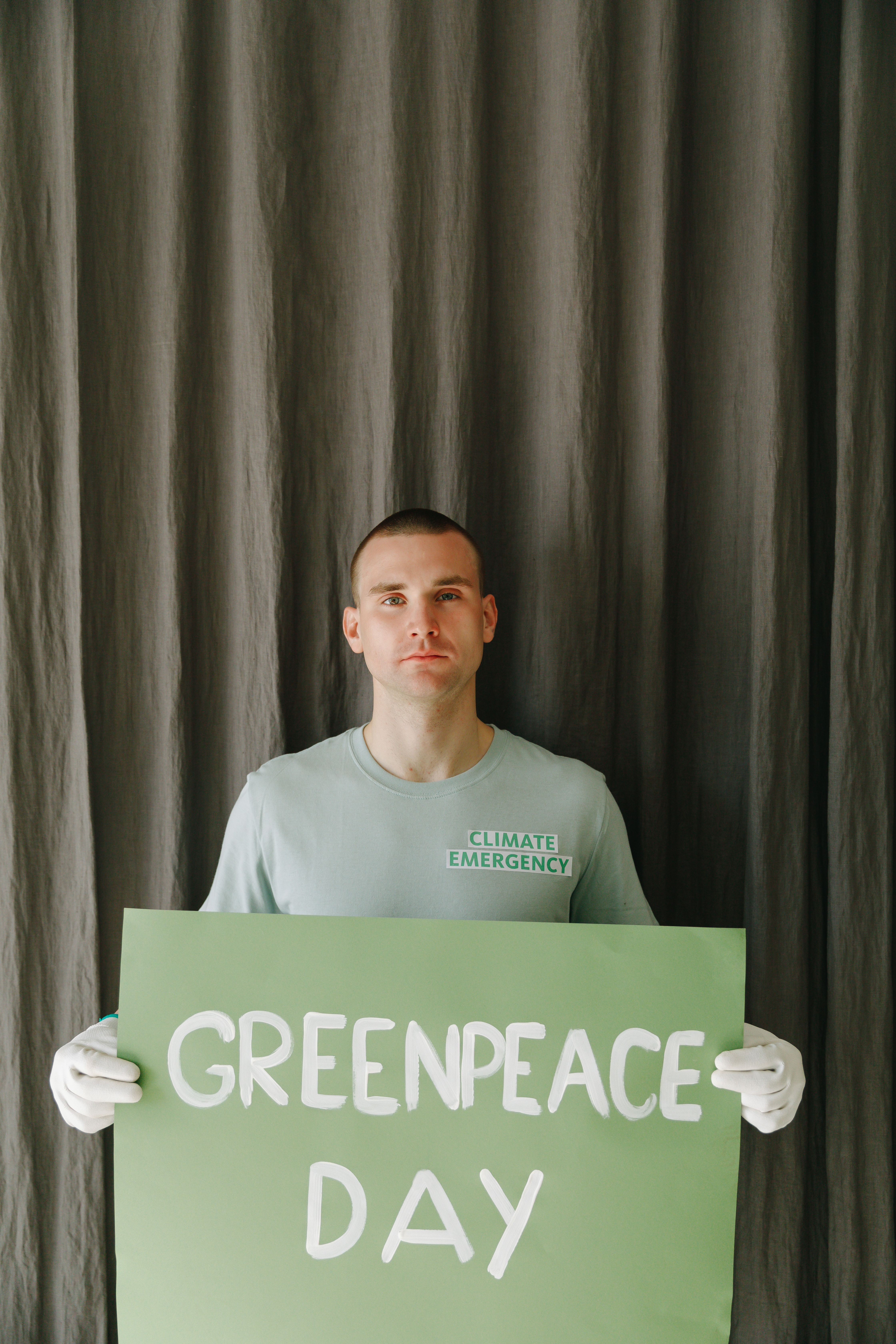 Portrait of an environmental activist holding Greenpeace Day sign indoors