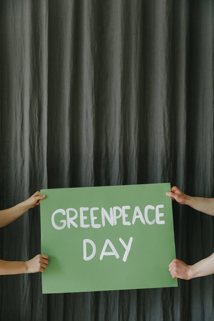 People Holding A Greenpeace Day Placard