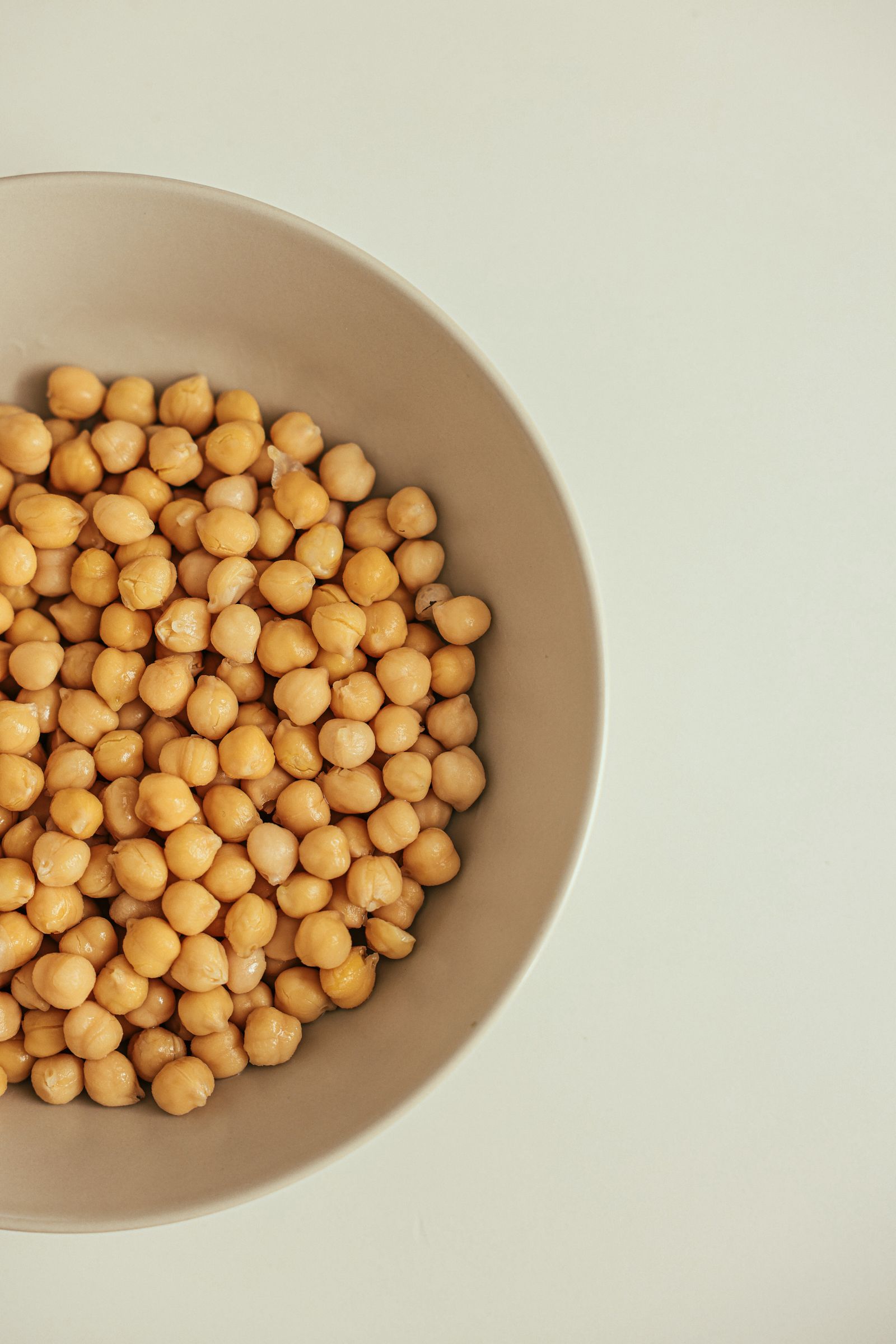 A close-up bowl of dried chickpeas, a legume high in fermentable GOS sugars that can trigger gas and bloating