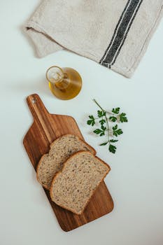 Two slices of wheat bread on a wooden board with olive oil and parsley.