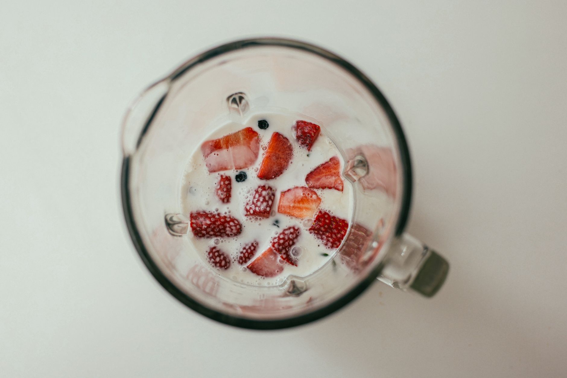 Fresh strawberries and milk in a blender viewed from above, perfect for healthy eating concepts.