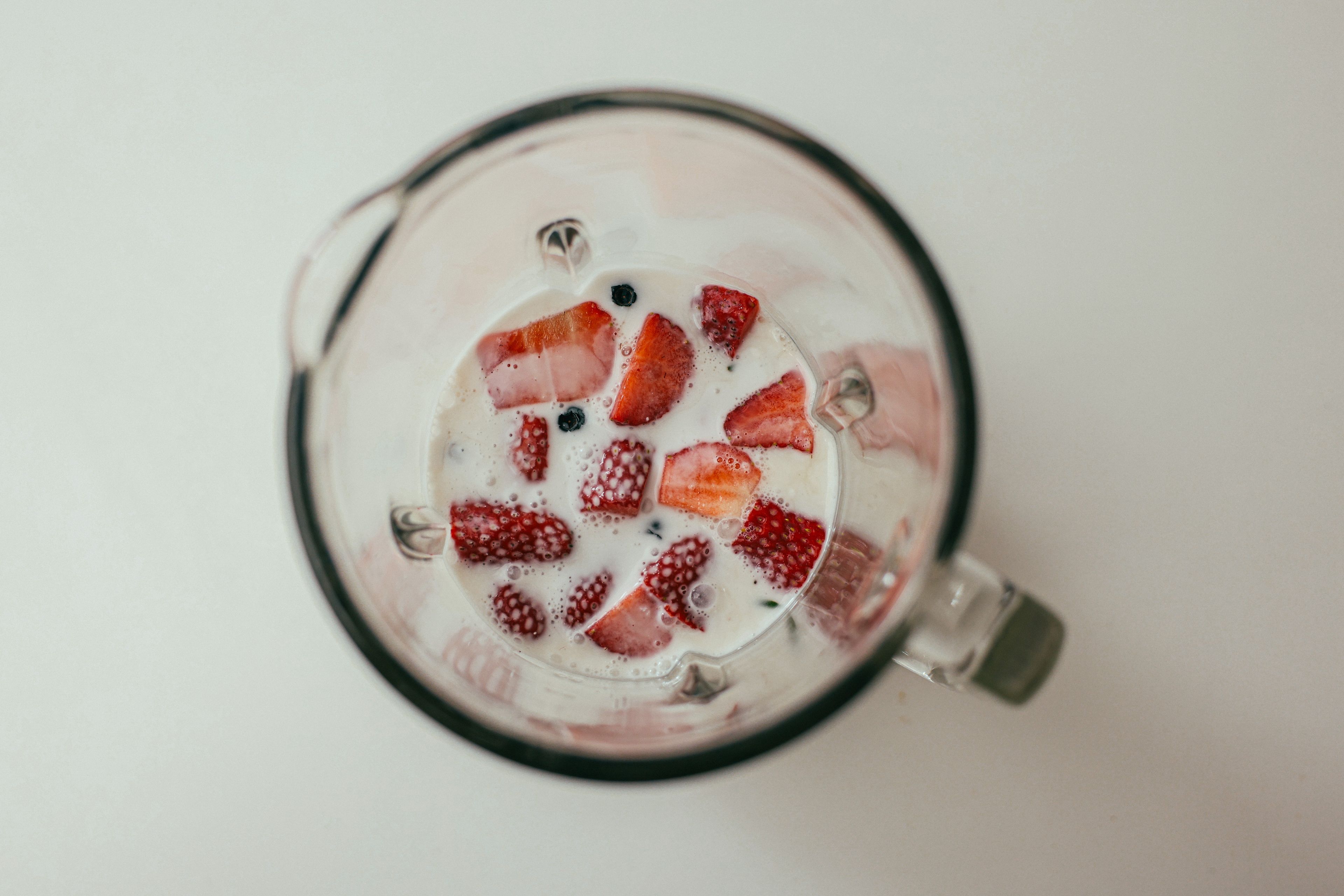Fresh strawberries and milk in a blender viewed from above, perfect for healthy eating concepts.