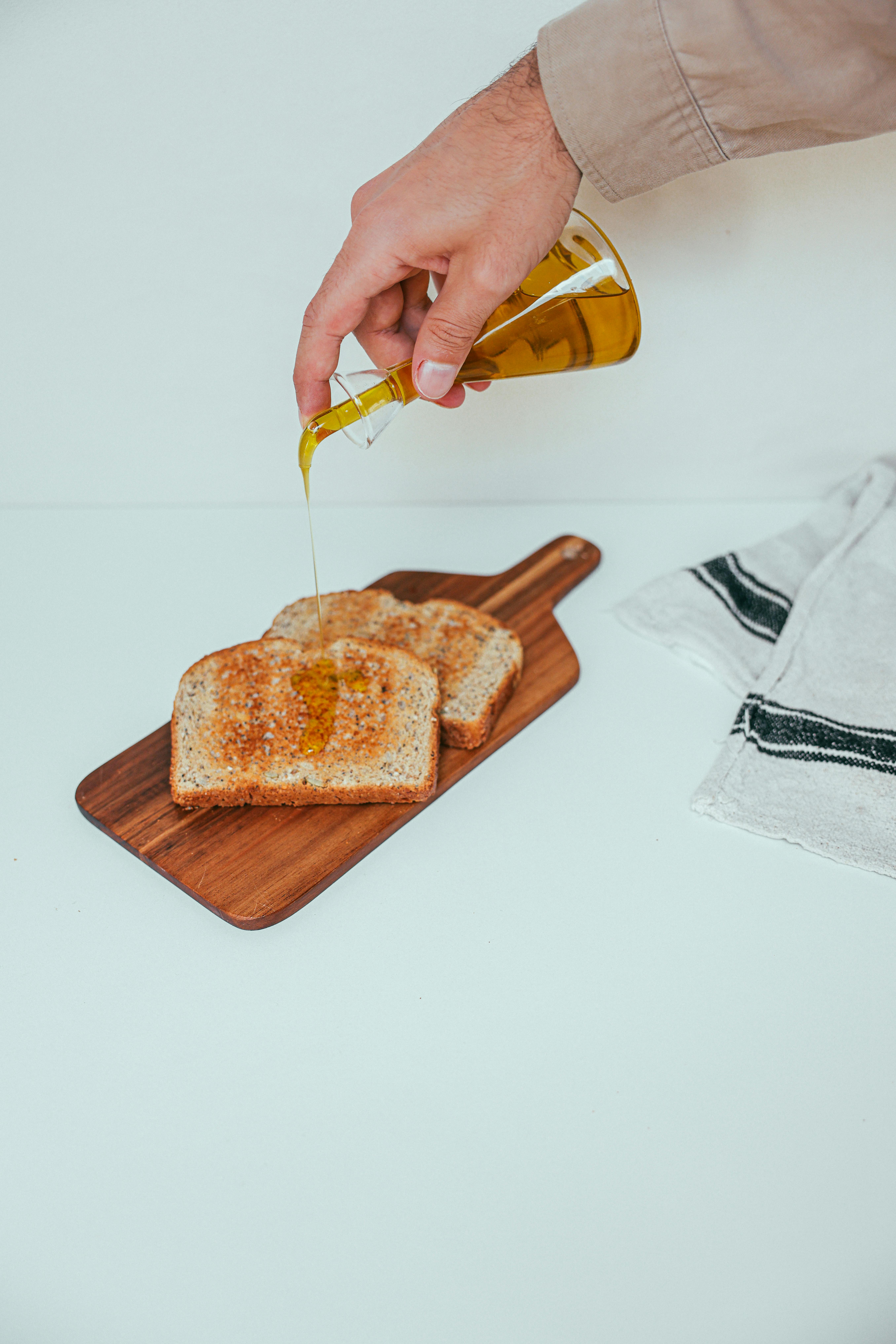 hand pouring olive oil on wheat bread
