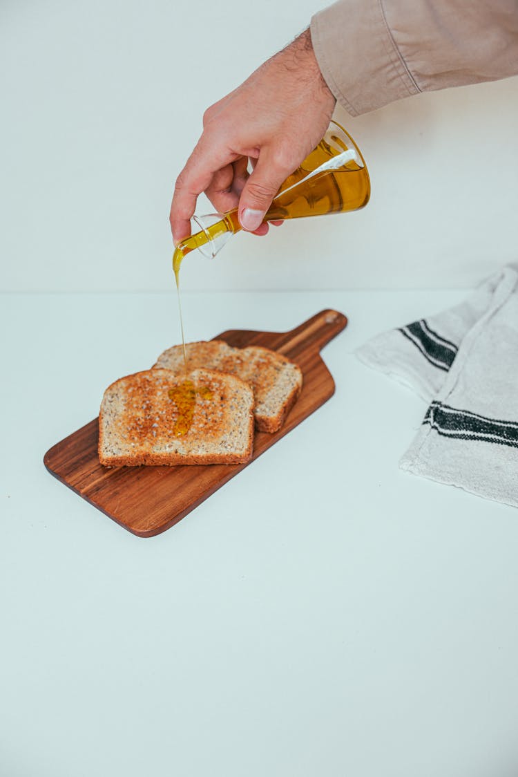 Hand Pouring Olive Oil On Wheat Bread