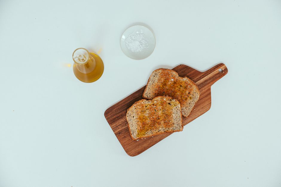 Top view of wheat toast with olive oil and salt on a cutting board.