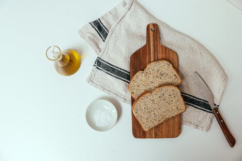 Free A Chopping Board on Towel with Slices of Bread Beside Olive Oil and Salt Stock Photo