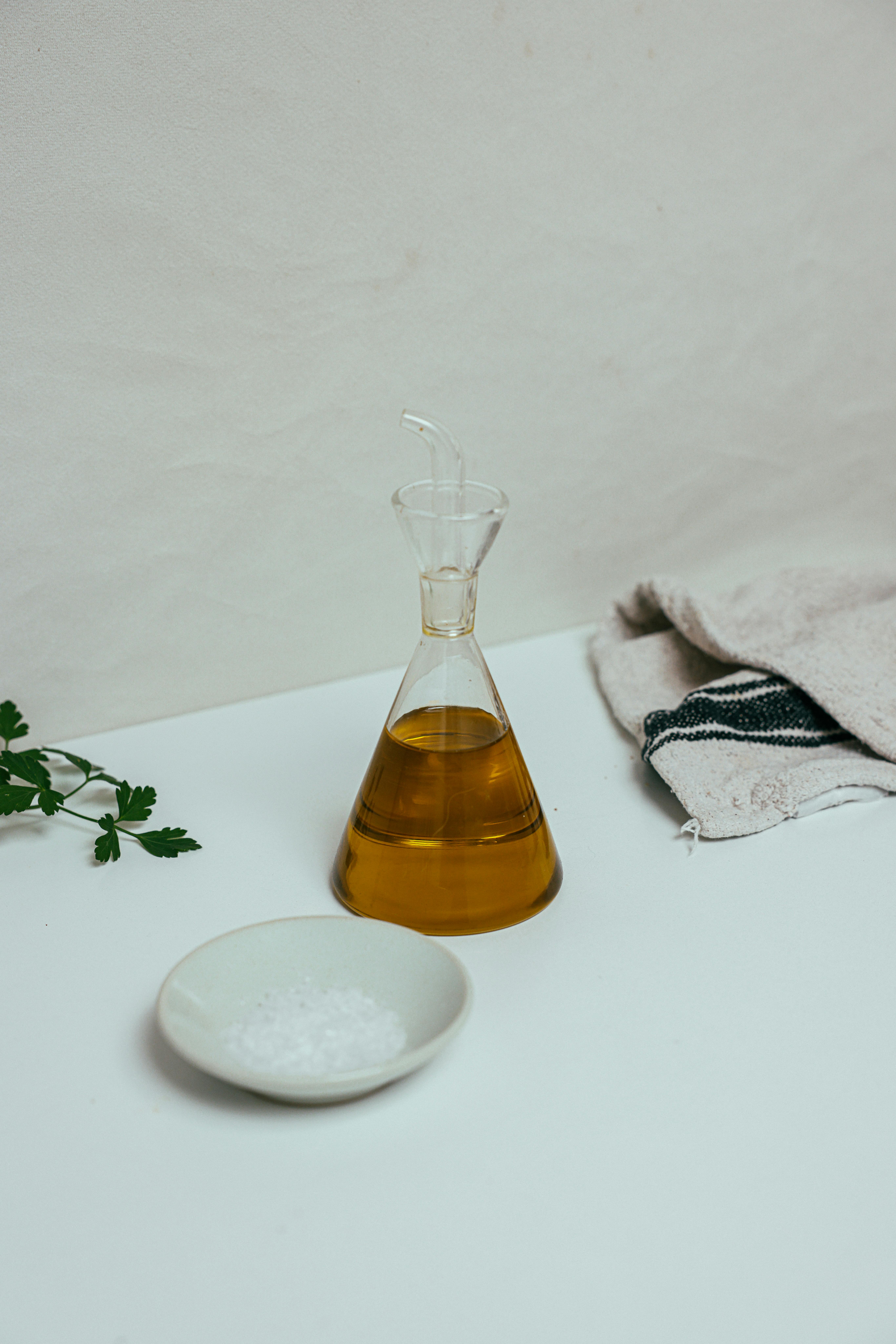 Free Bottle of Olive Oil Beside a White Saucer Stock Photo