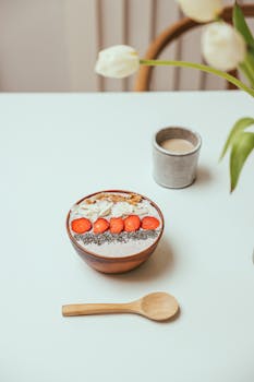 Delicious healthy breakfast bowl with strawberries, chia seeds, and almonds on a white table.