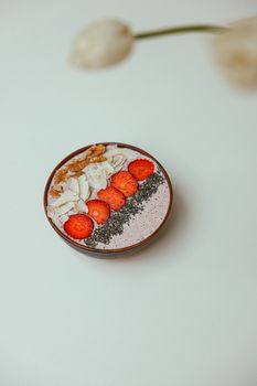 A vibrant smoothie bowl topped with strawberries, chia seeds, nuts, and coconut flakes.
