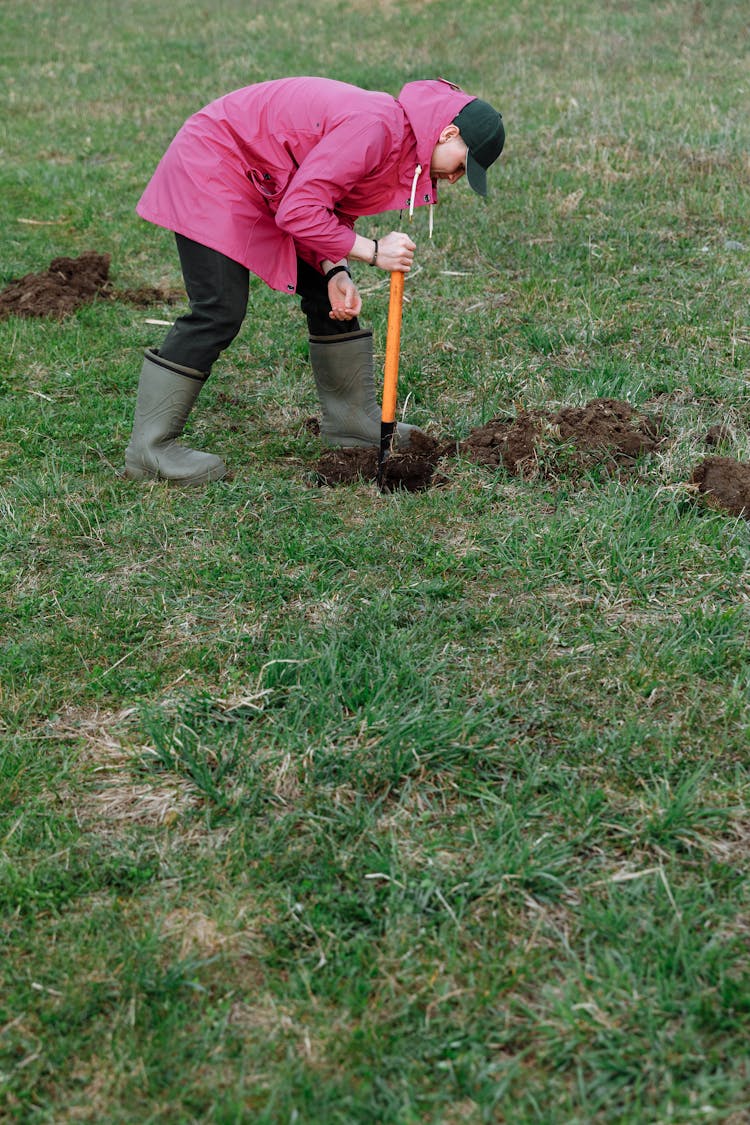 Person Digging On A Grassfield