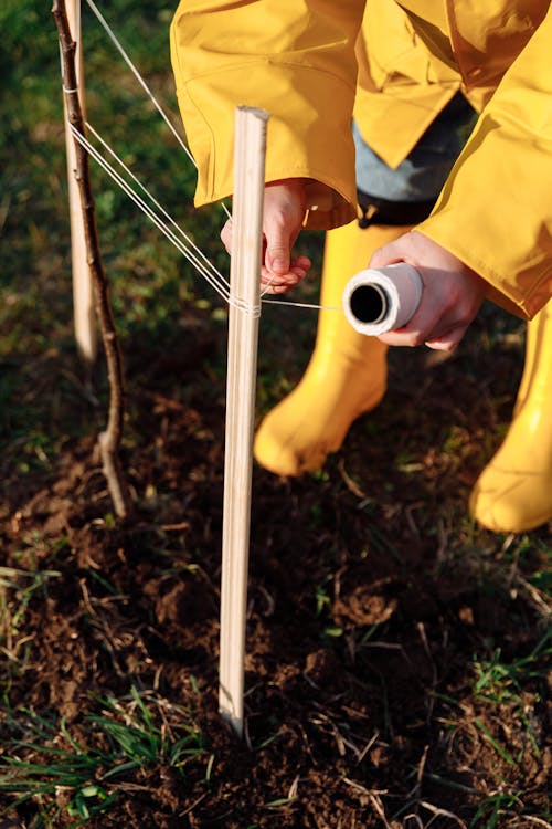 Person in Yellow Pants Holding White Metal Rod