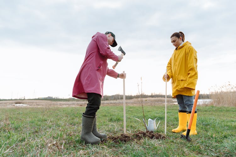 A Couple Planting On Green Grass Field