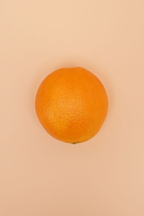 Free Bright orange fruit against a soft peach background, top-down view. Stock Photo