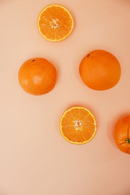 Free Fresh oranges on a peach background, showcasing juicy slices and whole fruits. Stock Photo