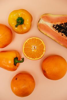 Vibrant top view of oranges, yellow peppers, and papaya on a warm background.