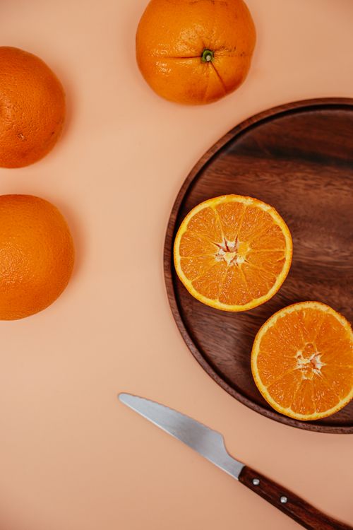 Free Top view of whole and sliced oranges on a wooden tray with a knife, perfect for healthy eating concepts. Stock Photo