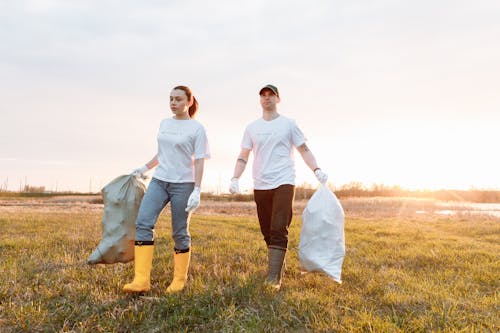 Free A Man and a Woman Holding Sacks of Garbage Stock Photo