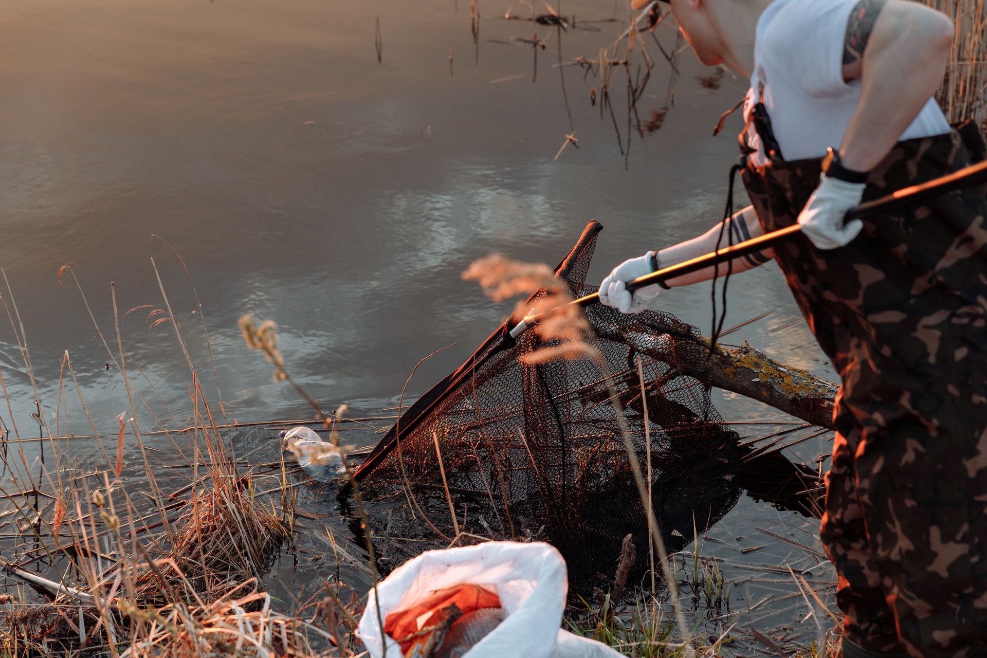 A Person Using a Net to Scoop Garbage from a Lake