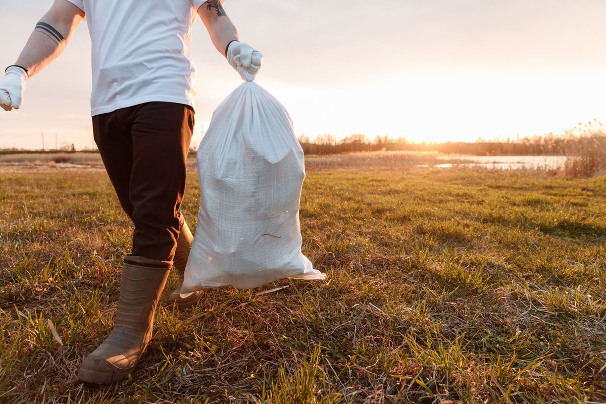Volunteer carrying a bag of collected litter across a field