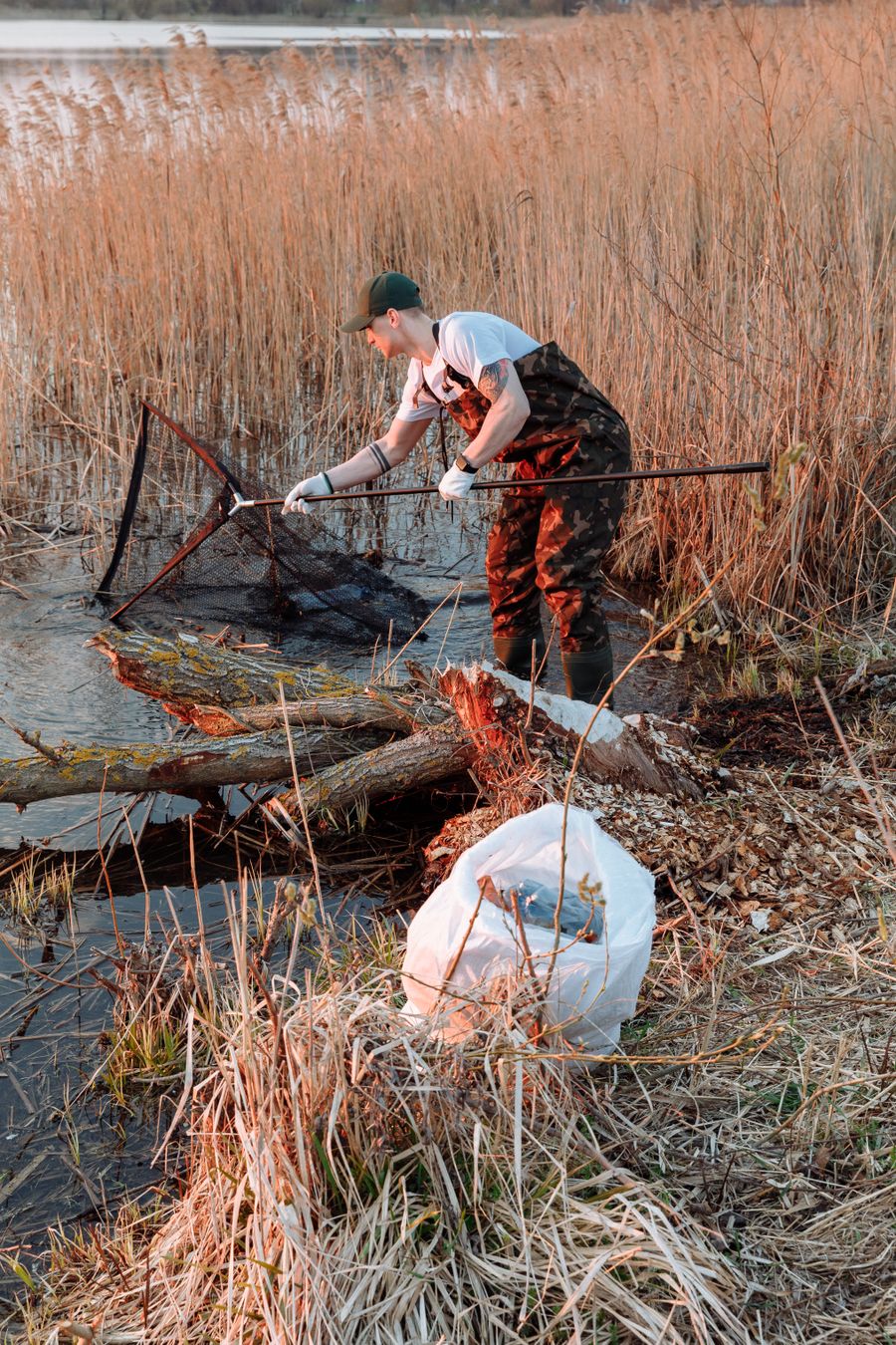 A fellow wading in a shallow creek, netting debris during a training survey