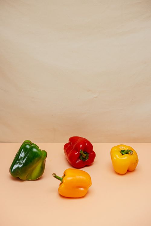 Free Four bell peppers in vibrant colors placed on a soft background with ample copy space. Stock Photo