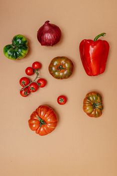 Flat lay of colorful organic vegetables including bell pepper, tomatoes, and onion.
