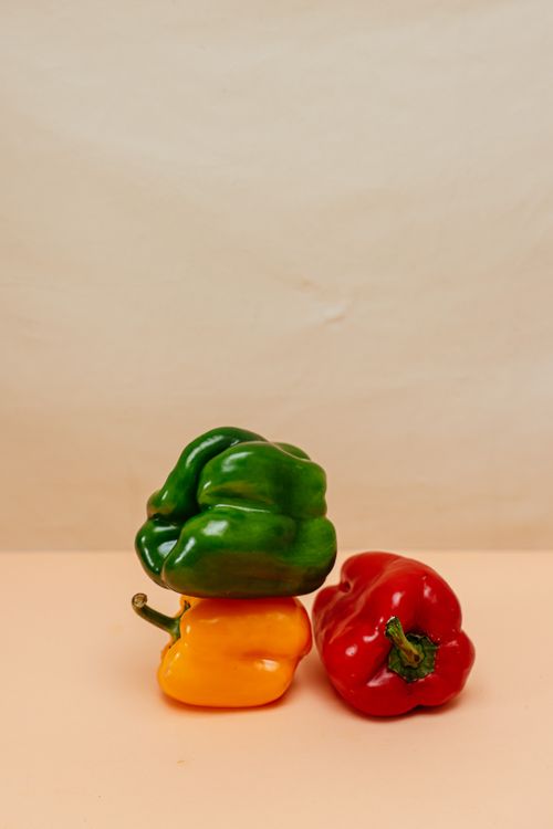 Free Colorful bell peppers stacked creatively against a neutral background. Stock Photo