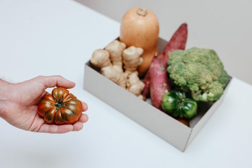 Free A collection of organic vegetables with a hand holding a tomato, perfect for food photography Stock Photo