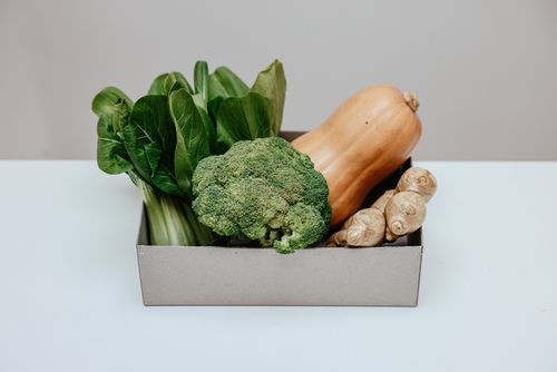 Free Box of fresh vegetables including broccoli, ginger, and squash on a white table. Stock Photo