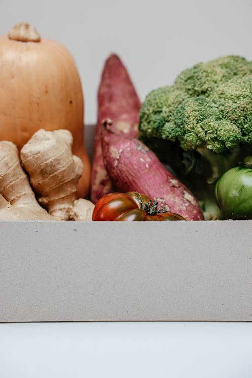 Free A variety of fresh organic vegetables including ginger, sweet potatoes, and broccoli in a cardboard box. Stock Photo