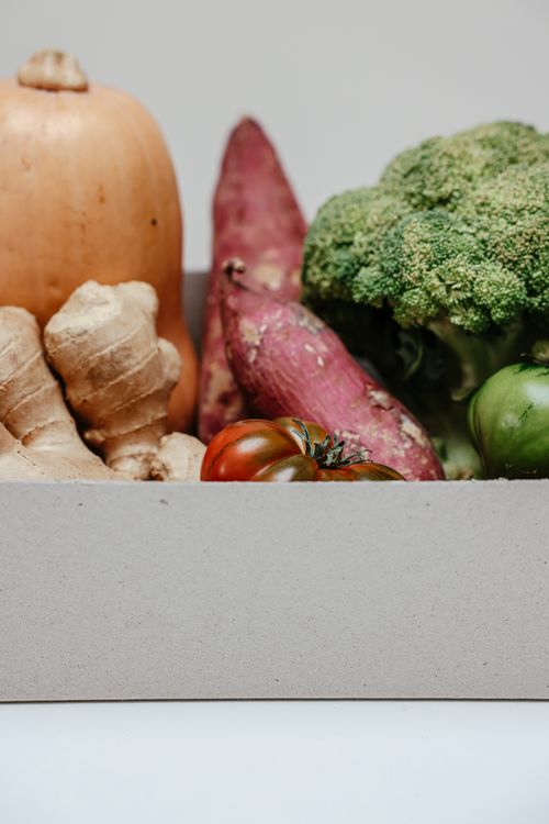 Free A variety of fresh organic vegetables including ginger, sweet potatoes, and broccoli in a cardboard box. Stock Photo