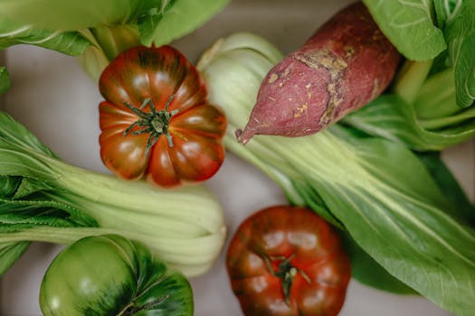 Fresh vegetables including heirloom tomatoes and sweet potato in a close-up setting.