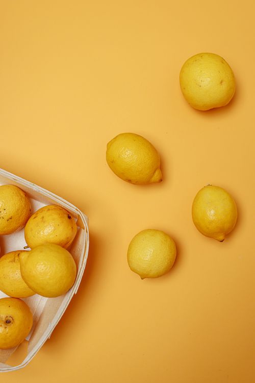 Free Bright lemons scattered on a vibrant yellow background, creating a fresh and juicy still life composition. Stock Photo