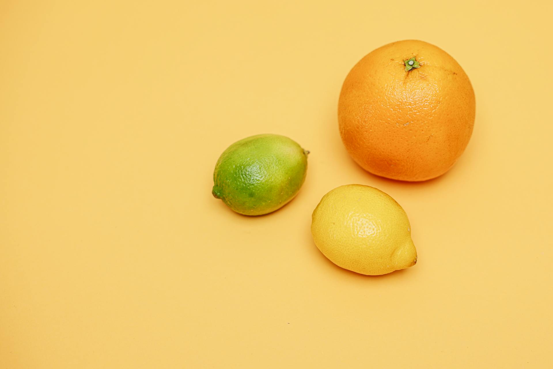 An Orange Fruit Beside Lime and Lemon