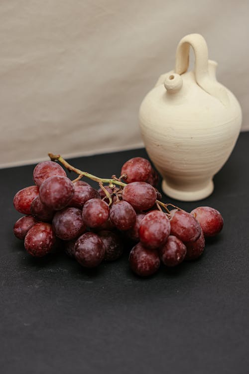 Red Grapes Beside White Ceramic Vase
