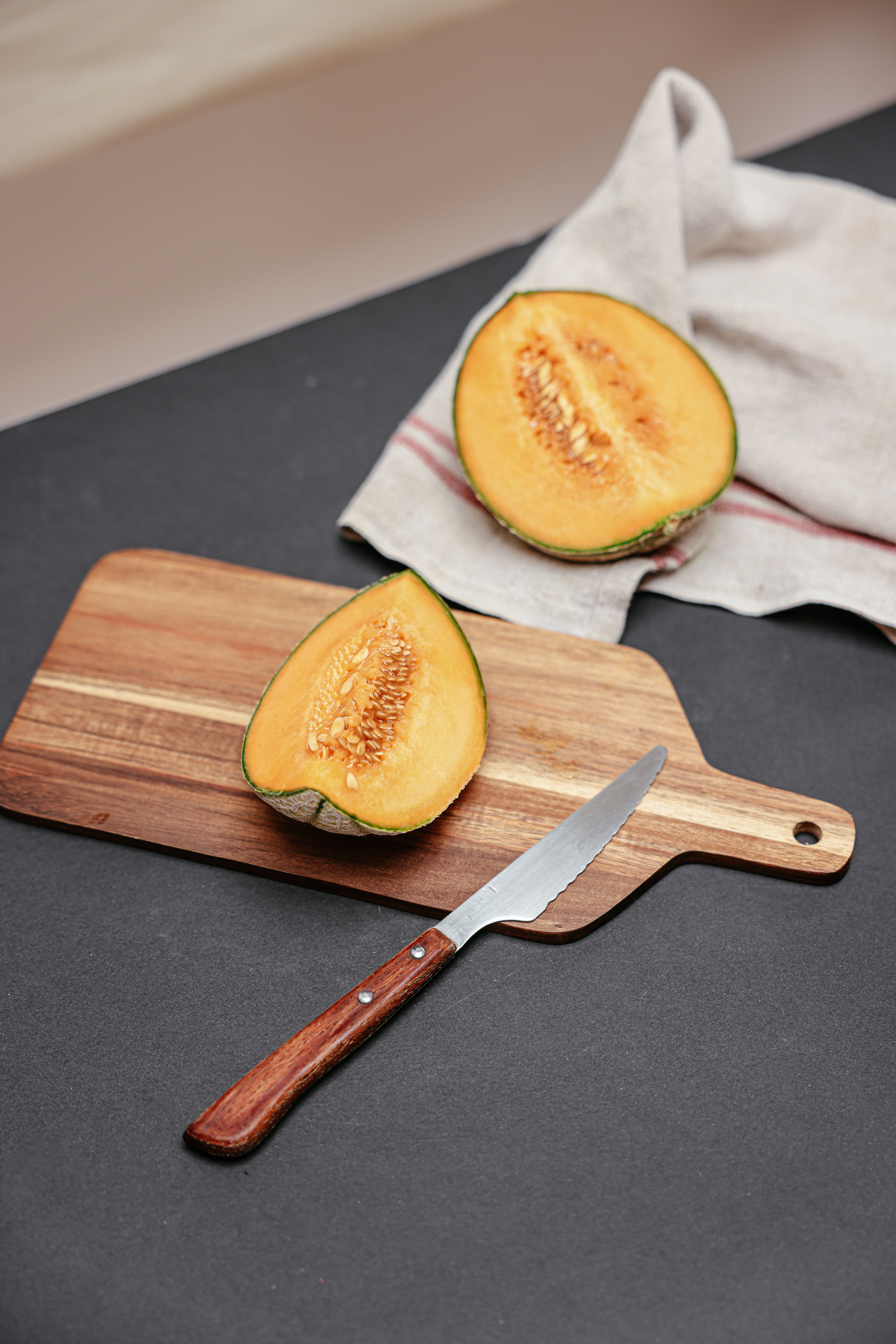 Sliced melon on a cutting board with knife, ideal for fresh fruit presentations.