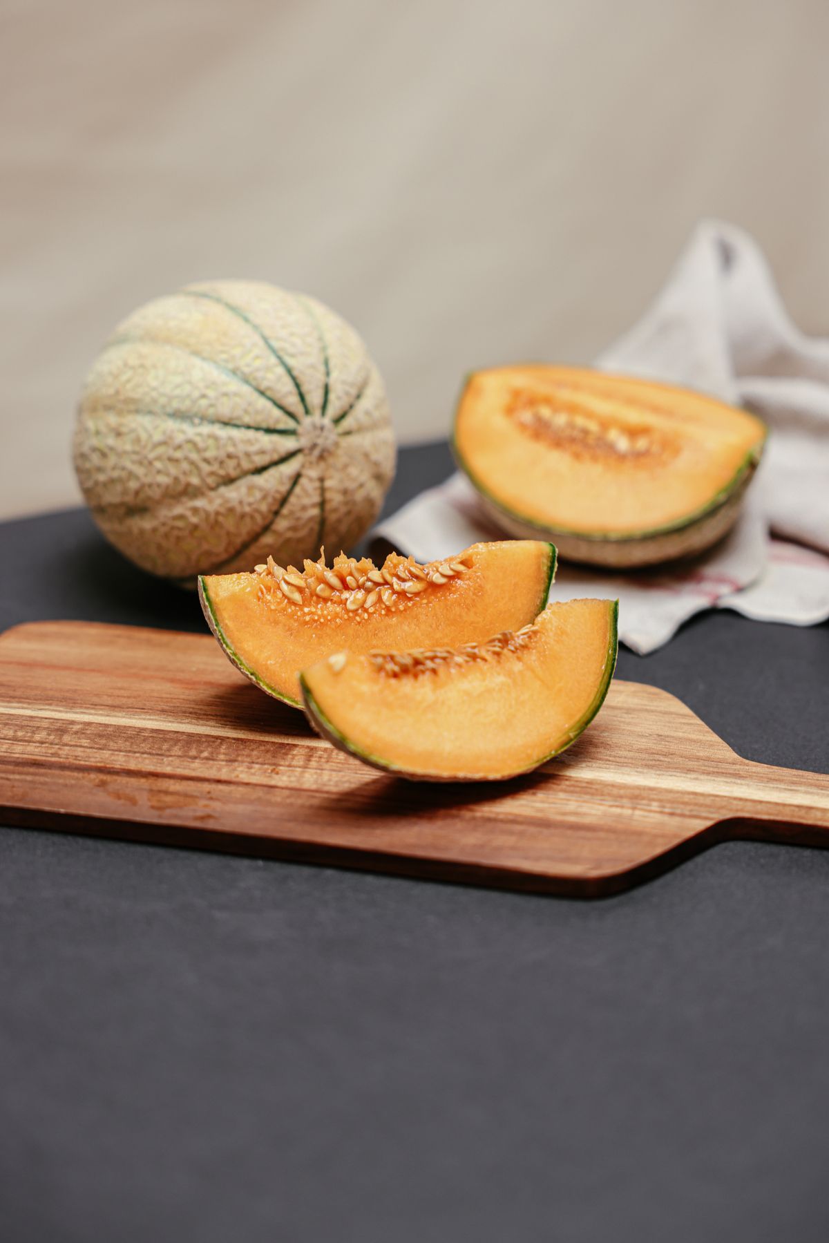 Sliced ripe cantaloupe melon on a wooden board, showing orange flesh