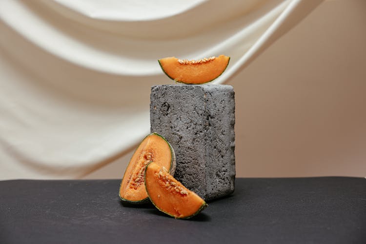 Sliced Of Melon Fruit On A Concrete Block