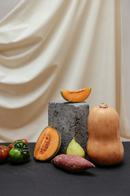 Free An artistic still life featuring a variety of fresh fruits and vegetables on a stylish backdrop. Stock Photo