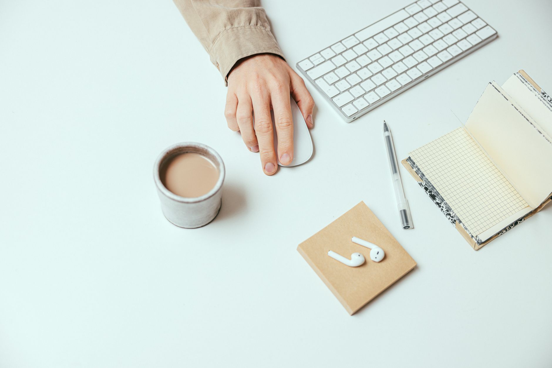 Top view of a modern minimalist workspace with airpods, coffee, and a keyboard.