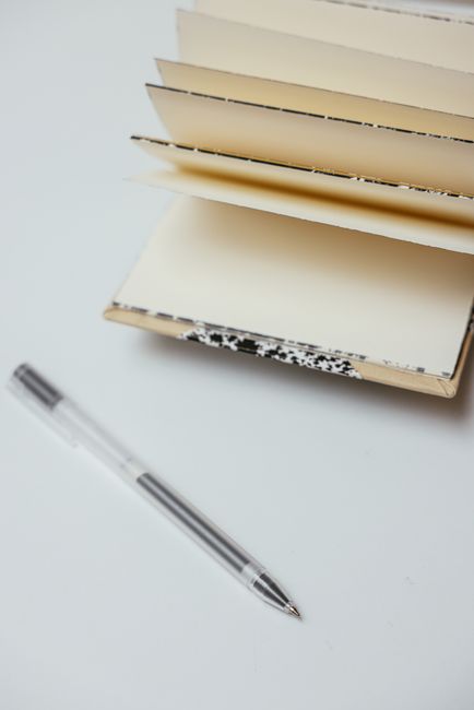 A pen resting beside an open pocket notebook