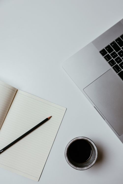 Free A clean, minimalist desk setup featuring a laptop, notebook, and coffee cup for productive work. Stock Photo