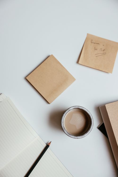 Free Flat lay of a minimalist workspace with coffee, notebooks, and sticky notes on a clean table. Stock Photo